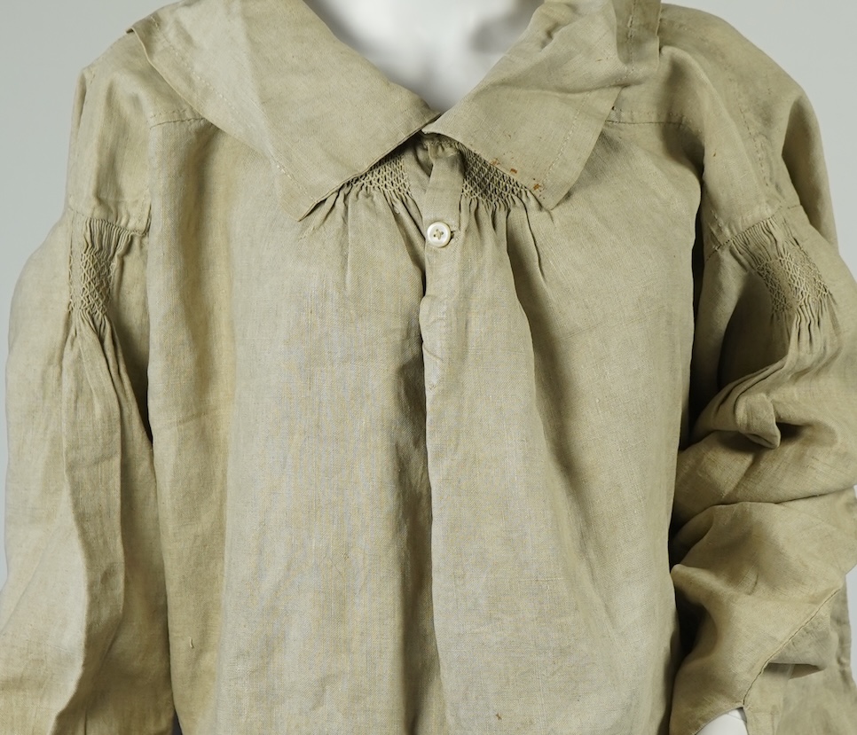 A 19th century heavy linen Shepherd’s smock, with small smocked shoulders and front and back neck panels under collar., 97cm long. Condition - patched and small darn near top and minor wear, usual for age and use.